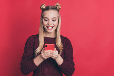 Photo of amazing influencer lady holding telephone in hands reading positive comments in blog post wear knitted jumper isolated pastel red color backgroundの写真素材