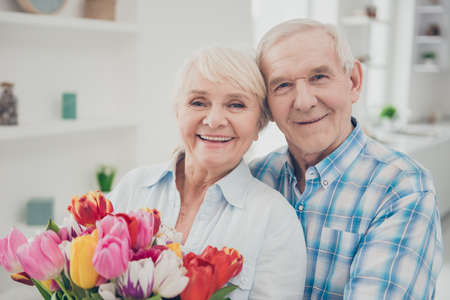 Close-up portrait of her she his he two nice attractive lovely cheerful cheery adorable people granny holding in hands big fresh natural blossom congrats spring in light white interior living-roomの写真素材