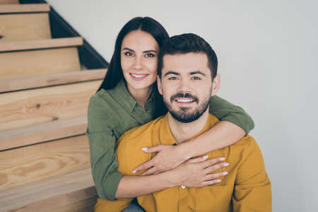 Closeup photo of handsome guy and his pretty lady sitting on stairs in modern interior room indoors moving to new flat house together wear casual clothesの写真素材