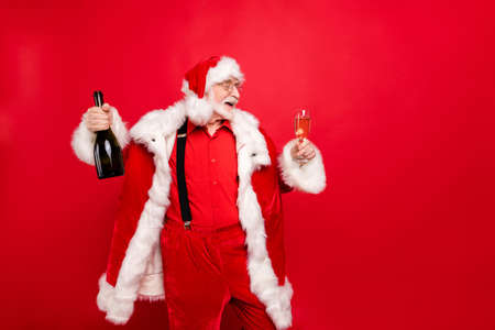 Portrait of his he nice carefree cheerful cheery bearded Santa Claus drinking champagne celebrating night isolated over bright vivid shine vibrant red backgroundの写真素材