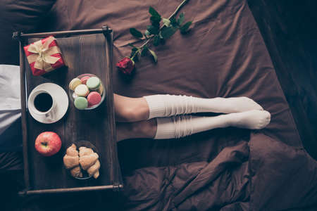 Cropped top above high angle view of nice attractive girl lying on bed long legs enjoying romance occasion event fresh delicious snack on sheets linen at house flat apartment indoorsの写真素材