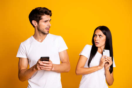 Photo of two people with telephones not trust each other private information wear casual clothes...