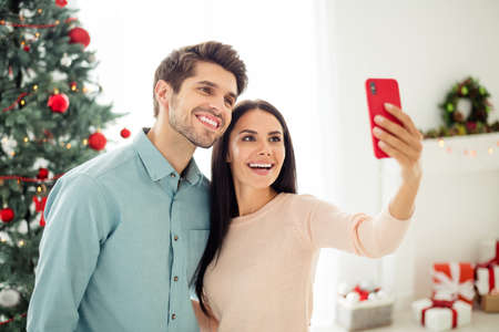 Portrait of two people lovely man and woman making selfie with their cell phone enjoy christmas time...