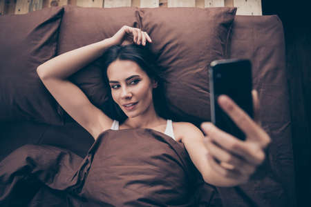 Portrait of her she nice attractive lovable lovely charming alluring cheerful girl taking making selfie sending photos lying in bed in room flat house indoorsの写真素材