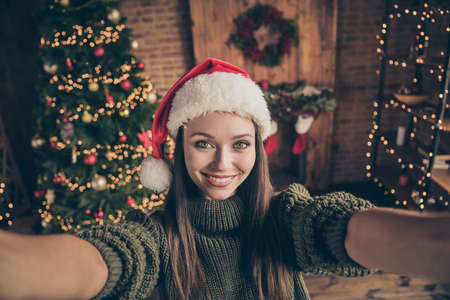 Close up photo of positive cheerful girl newyear blogger influencer take selfie video call show her christmas party time preparation in house full of garlands tinsels indoorsの写真素材