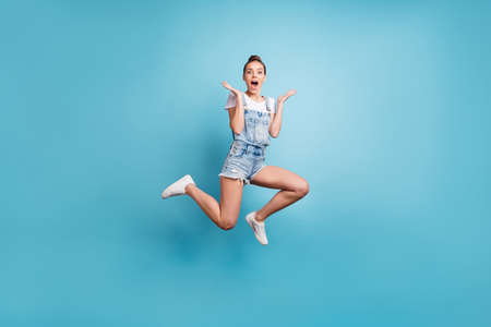 Full length body size photo of delighted astonished amazed girl seeing something unbelievable while isolated with blue backgroundの写真素材