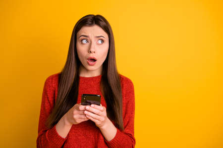 Photo of terrified stunned shocked horrified youngster holding telephone receiving negative feedback having forgotten her password to social media isolated vibrant color backgroundの写真素材