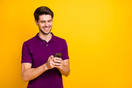 Photo of white cheerful handsome attractive man browsing through, his telephone chatting with friends isolated over vivid color backgroundの写真素材