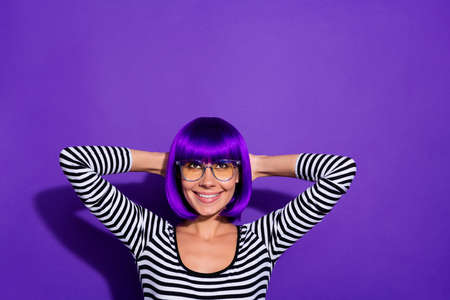 Photo of nice lady hold hands behind head overjoyed look empty space wear wig striped pullover isolated purple backgroundの写真素材