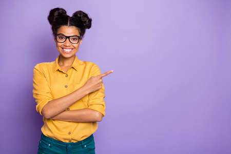 I have good news. Photo of amazing dark skin lady indicating finger to empty space advising novelty wear specs yellow shirt isolated purple color backgroundの写真素材