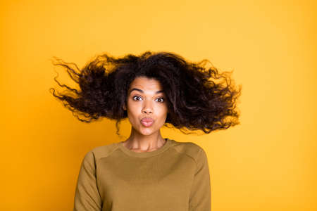 Closeup photo of amazing pretty dark skin lady warm fall breeze throwing hairdo up air sending kiss wear casual pullover isolated on yellow color background