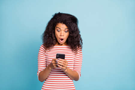 Photo of astonished grimacing black youngster holding telephone with hands staring in wearing...