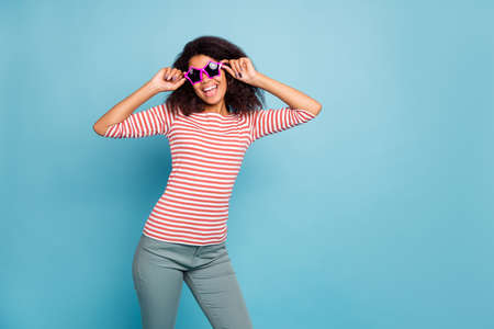 Its friday oclock. Photo of funny dark skin lady ready start party wear star shaped sun specs casual clothes isolated pastel blue color backgroundの写真素材