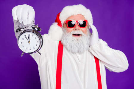 Photo of funny overweight santa father holding alarm clock remind its newyear oclock crazy mood wear sun specs costume isolated purple backgroundの写真素材