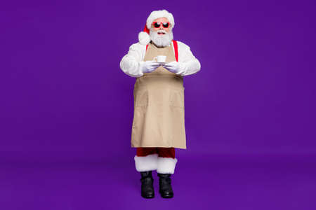 Full length body size view of his he nice cheery cheerful bearded thick fat Santa giving offering you sharing espresso cup isolated over bright vivid shine vibrant violet lilac backgroundの写真素材