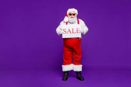 Full length body size view of his he nice confident cheerful cheery bearded thick fat Santa holding...