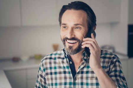 Close up photo portrait of satisfied cheerful optimistic man with modern hairstyle using cellular talking to his best fellowの写真素材