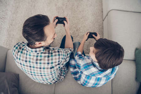 Top above high angle view portrait of two nice attractive guys dad and pre-teen son sitting on couch enjoying playing video game pad spending spare time in living-roomの写真素材