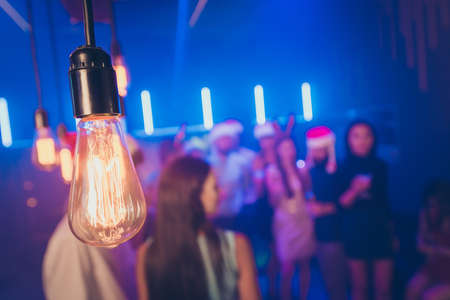 Closeup photo of old-fashioned light bulb making miracle atmosphere, party crowd best friends on...