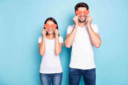 Portrait of his he her she nice attractive funny funky comic cheerful cheery couple holding in hands small little hearts closing eyes isolated on bright vivid shine vibrant blue turquoise backgroundの写真素材