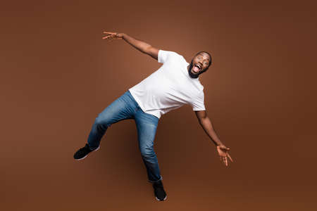 Full length body size view of his he attractive funny cheerful cheery crazy guy having fun fooling isolated over dark brown platinum pastel color backgroundの写真素材