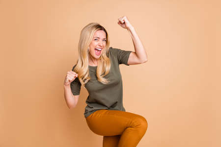 Photo of cheerful positive cute nice pretty fascinating girl wearing yellow pants trousers green overjoyed about having won jackpot screaming isolated beige pastel color backgroundの写真素材
