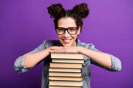 Photo of funny student lady holding many books carry literature home in love with reading wear specs casual denim outfit isolated purple color backgroundの写真素材
