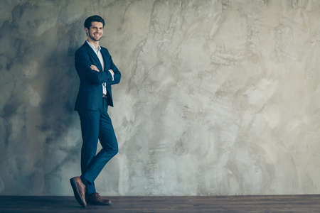 Best company owner ever concept. Young millionaire stunning charming businessman stand lean wall cross hands feel proud wear modern blue jacket pants isolated over grey color backgroundの写真素材