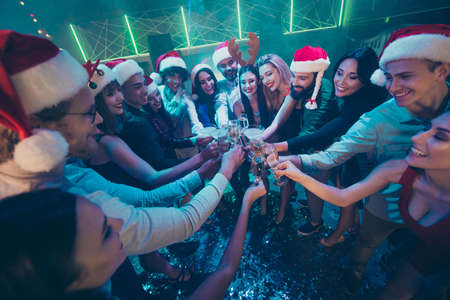 Photo of party crowd best friends holding sparkling wine glasses counting last seconds to newyear festive mood wear dresses shirts pants santa hat in night clubの写真素材