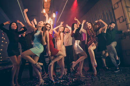 Lets party hard. Low angle view full body photo of positive cheerful youth people want celebrate high-school graduation event weekend feel crazy wild wear formalwear skirt high-heels in nightclubの写真素材