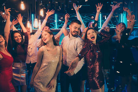 Photo of dancing people dressed in formalwear rejoicing good free time together with macho surrounded by girls hanging out between them in falling confettiの写真素材