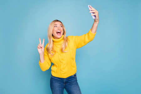 Photo of amazing blond lady holding telephone hands showing v-sign symbol making selfies wear...
