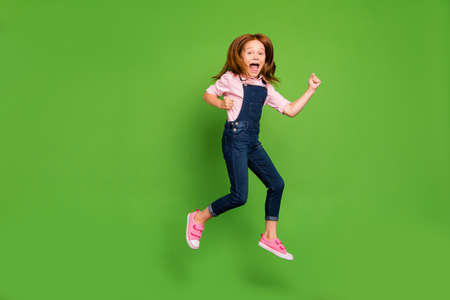 Full length photo of cheerful pretty little schoolchild jumping high rejoicing summer holidays start...