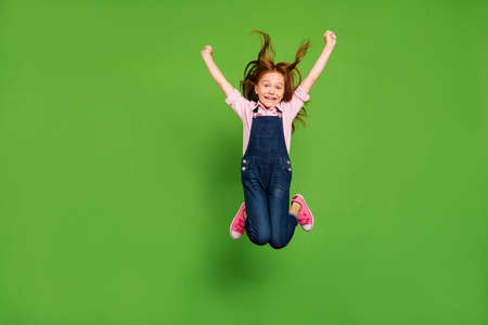Full body photo of pretty little schoolchild jumping high rejoicing summer holidays hair flying warm...