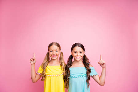 Photo of two beautiful small ladies best friends indicating fingers up empty space advising new low...