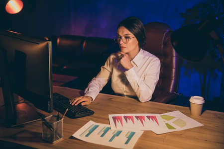 Portrait of nice attractive stylish chic concentrated lady top executive manager company agency owner preparing report plan strategy investment ratio result at night dark work place stationの写真素材