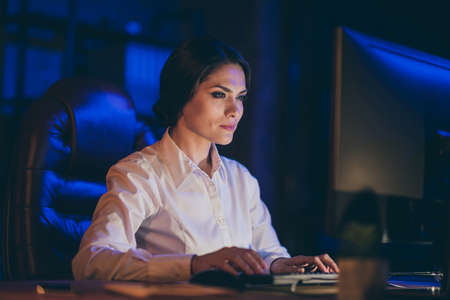 Close-up portrait of nice attractive lovely gorgeous stylish skilled lady hard-working top executive manager leader preparing marketing finance report deadline at night dark work place stationの写真素材