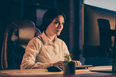 Close-up portrait of her she nice attractive gorgeous lovely charming focused busy lady copywriter typing creating presentation report analysis at night dark workplace workstation indoorsの写真素材