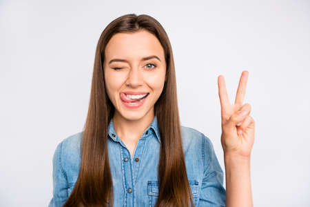 Close up photo of positive cheerful girl have fun lick lips wink blink make v-signs wear casual...