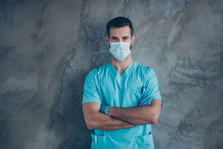 Photo of qualified professional doctor wearing facial mask with arms crossed specialist at surgery before starting operation isolated grey color wall concrete backgroundの写真素材