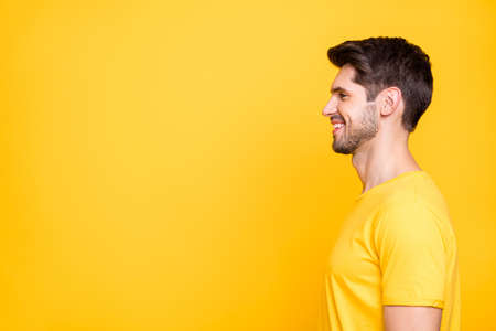 Profile photo of young handsome business guy freelancer looking, empty space toothy smiling wear casual t-shirt isolated bright yellow color backgroundの写真素材