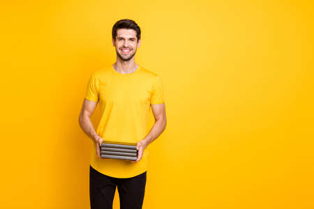 Photo of youngster handsome guy holding many books diligent student get scholarship raise wear casual t-shirt pants isolated yellow color backgroundの写真素材