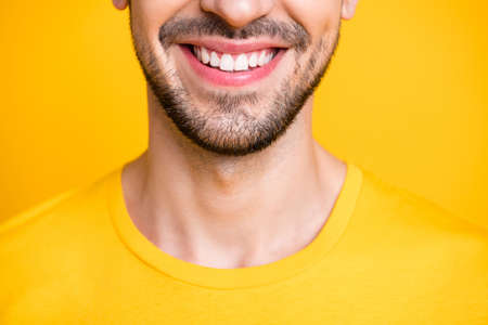 Closeup cropped photo of amazing macho guy looking mirror examining teeth after dental laser cleaning wear casual t-shirt isolated yellow color backgroundの写真素材