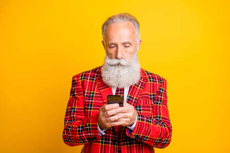 Close-up portrait of his he nice handsome attractive focused grey-haired man using, modern digital device 5g app isolated over bright vivid shine vibrant yellow color backgroundの写真素材