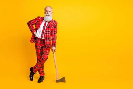 Full length photo of cool aged guy white beard holding ax hands play serial killer character at halloween wear tartan red costume outfit isolated bright yellow color backgroundの写真素材