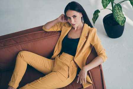 Top above high angle photo of gorgeous beauty rich lady lie on brown leather couch attract millionaire macho men wear stylish yellow vogue outfit in house indoorsの写真素材