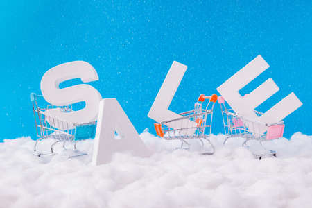 X-mas big season shopping sales concept. Photo of letters word sales stand under blue sky background in small supermarket mall center trolleys need buyers sellers carrying purchasesの写真素材