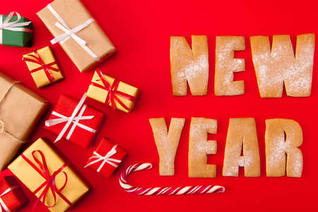 High angle above view photo of surprise newyear biscuits congrats two baked words decor figures tasty x-mas composition giftboxes candies isolated bright red backgroundの写真素材