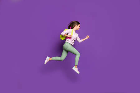 Full length body size profile side view of her she nice attractive lovely cheerful cheery girl jumping running high-school isolated on bright vivid shine vibrant purple violet lilac color backgroundの写真素材