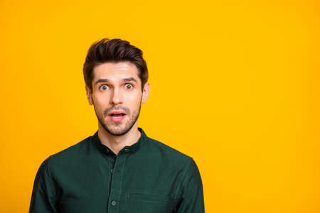 Photo of fearful man seeing terrible things occurring with negative stressful emotions on face in green shirt isolated vivid color backgroundの写真素材
